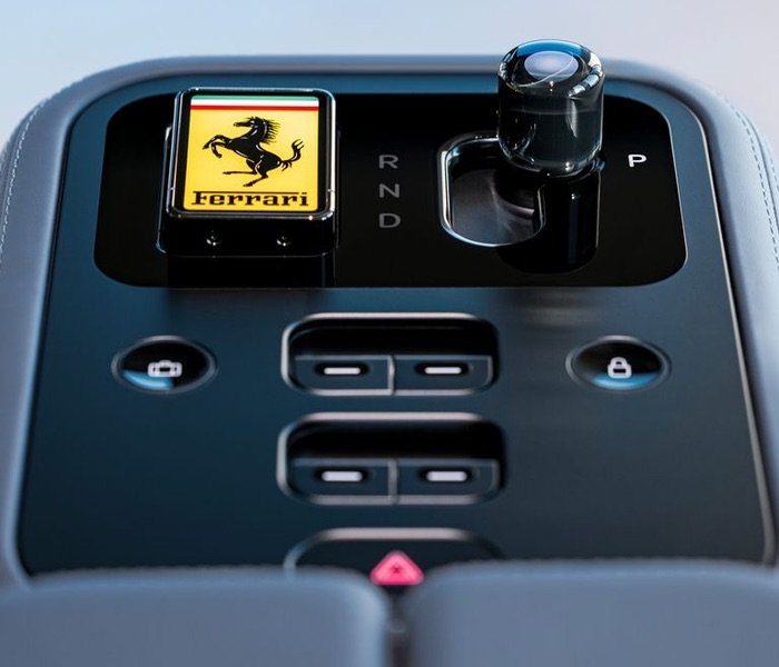 Primer plano de la consola central del Ferrari Luce diseñada por LoveFrom, mostrando el selector de marchas de cristal y el logotipo clásico de Ferrari